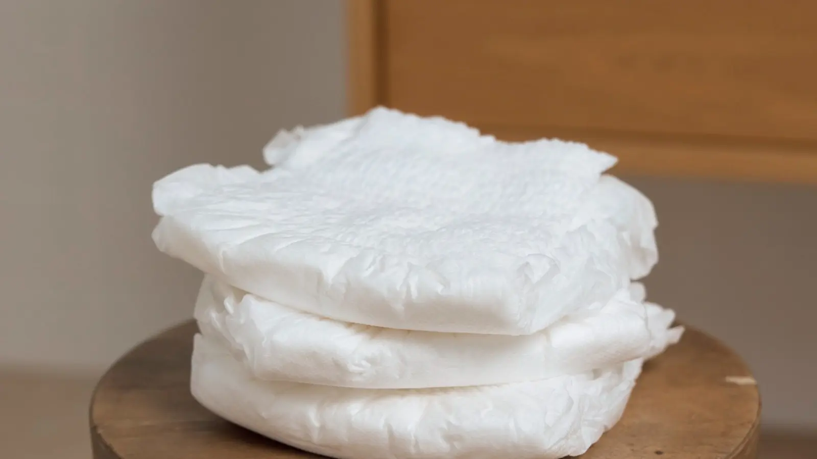 Folded Svelte pull-up continence underwear showing soft white product texture on a wooden stool.